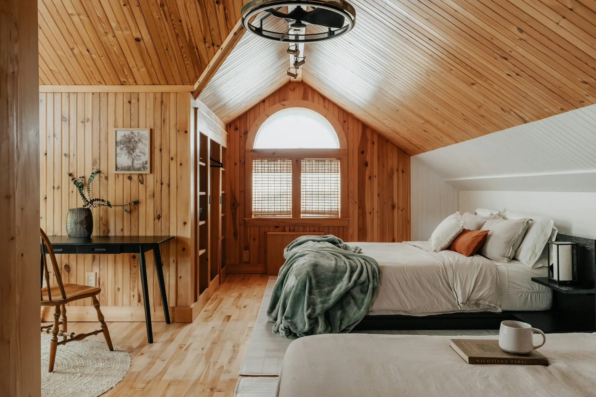 Schlafzimmer unter einer Holzdachschräge mit zwei Betten und rundem Fenster